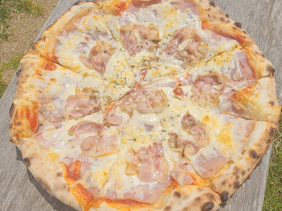 Pica s šunko in sirom na leseni mizi