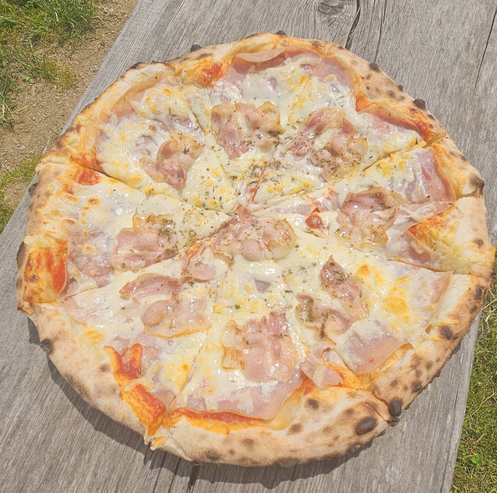 Pica s šunko in sirom na leseni mizi