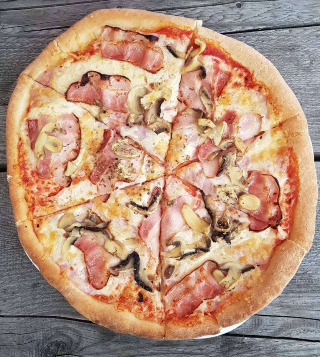 Pica s šunko in gobami na leseni mizi